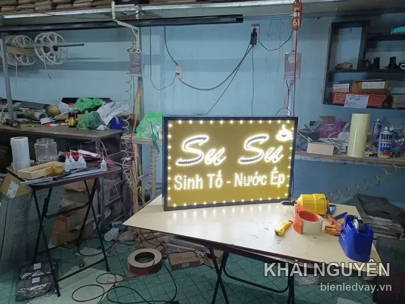 Biển vẫy LED nền vàng, chữ Su Su ghép từ bóng LED trắng, dòng Sinh Tố Nước Ép màu đen, viền LED bóng tròn chạy quanh khung.