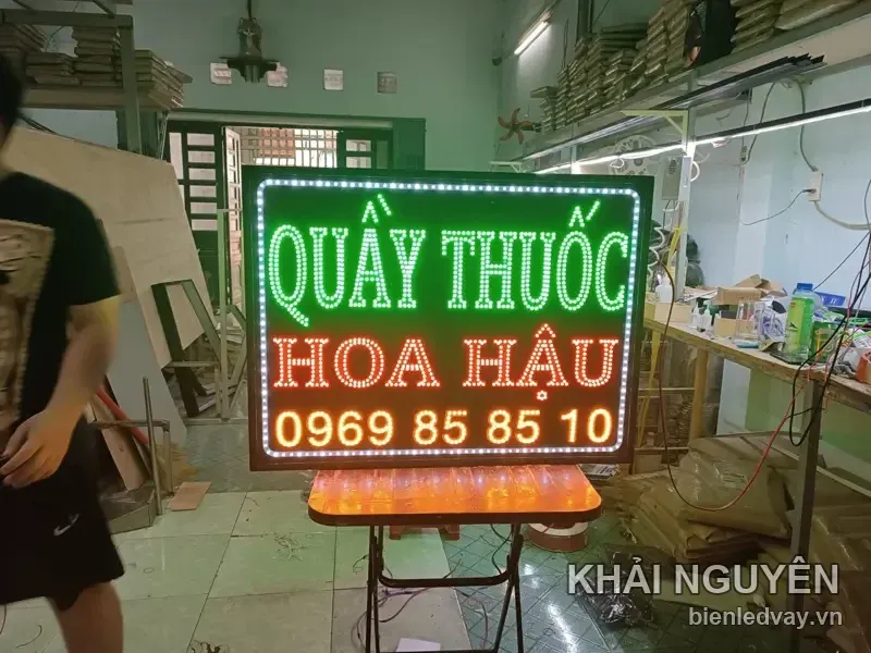 Biển Quầy Thuốc Hoa Hậu nền đen, chữ xanh lá và đỏ, viền LED bóng tròn trắng, có số liên hệ và đặt trên giá gấp