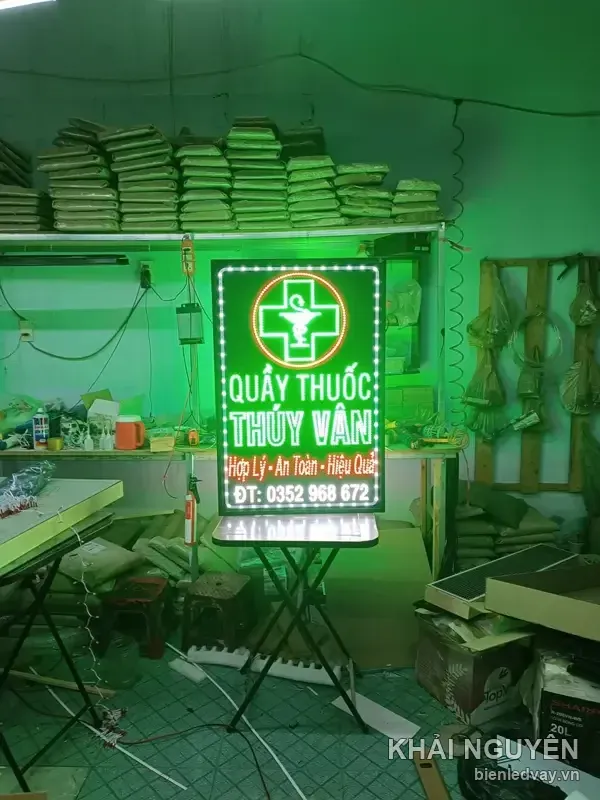 Biển vẫy QUẦY THUỐC THÚY VÂN có nền xanh lá, chữ trắng vàng, chữ thập dược viền LED tròn và dòng ĐT kèm số liên hệ.