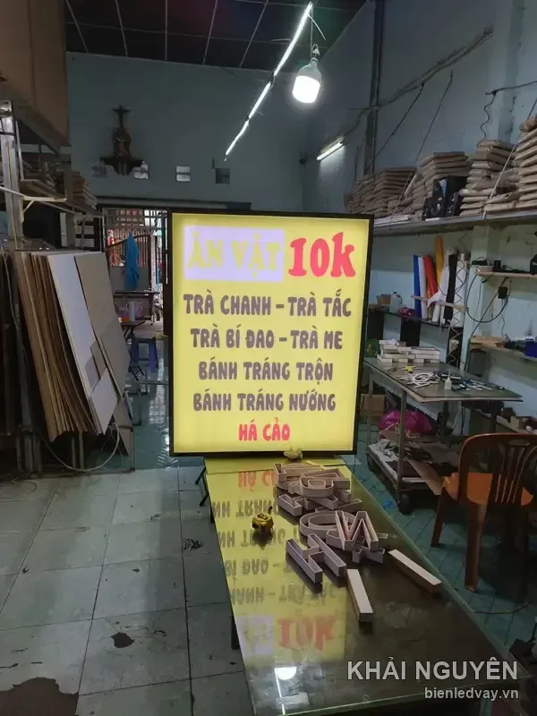 Hộp đèn quán trà chanh và đồ ăn vặt đang bật sáng trong xưởng