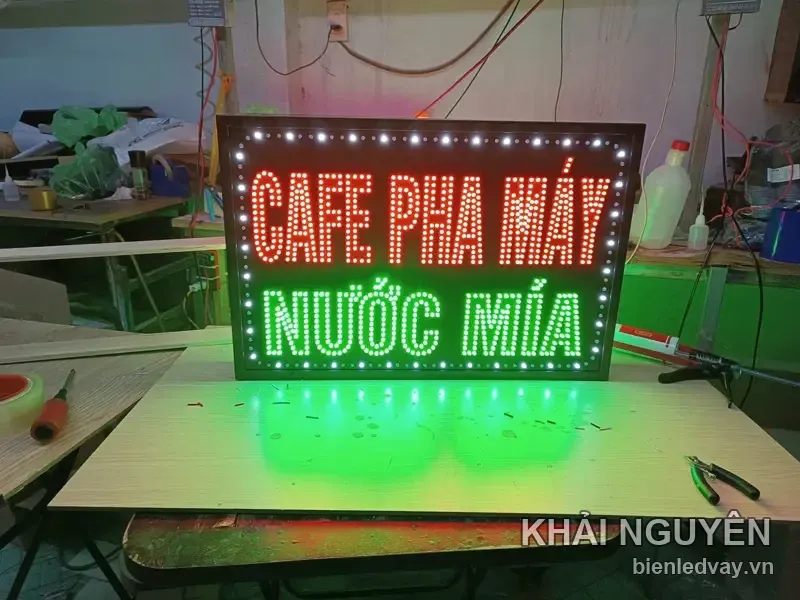 Biển vẫy nền đen, chữ ghép bóng LED: CAFE PHA MÁY màu đỏ ở trên, NƯỚC MÍA xanh lá ở dưới, viền bóng trắng chạy quanh