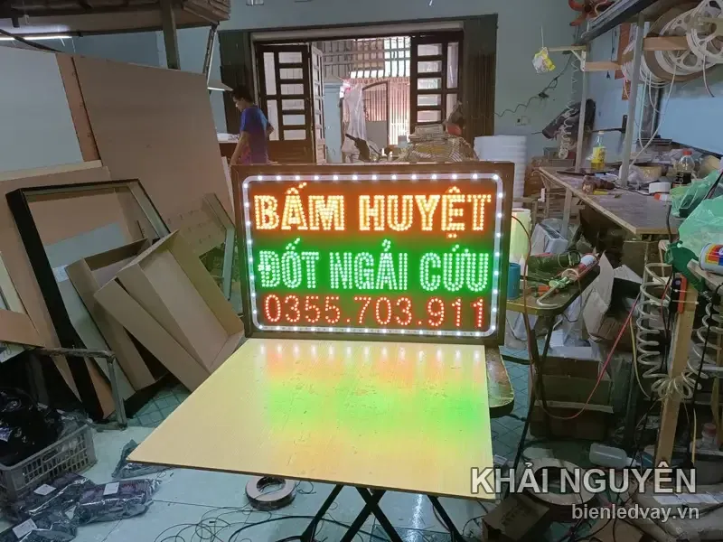 Biển vẫy nền đen chữ LED vàng BẤM HUYỆT, xanh lá ĐỐT NGẢI CỨU và số liên hệ trên biển màu đỏ, viền bóng tròn trắng
