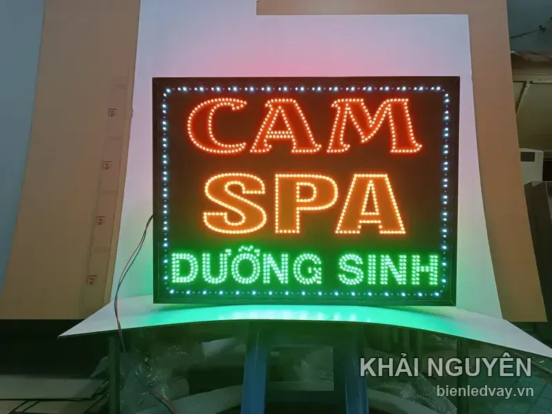 Biển vẫy CAM SPA chữ đỏ cam, dòng DƯỠNG SINH màu xanh lá, viền LED trắng chạy quanh nền đen