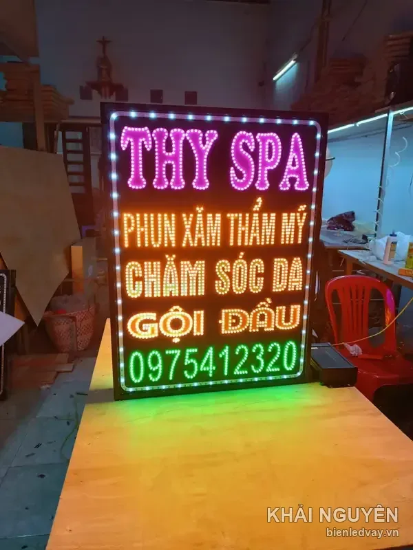 Biển vẫy Thy Spa nền đen, chữ LED hồng THY SPA, dòng cam vàng phun xăm thẩm mỹ và chăm sóc da, số liên hệ trên biển xanh lá