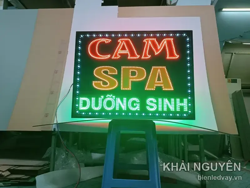 Biển vẫy LED Cam Spa dưỡng sinh đặt trên ghế nhựa, chụp chính diện lúc chạy thử đèn tại xưởng