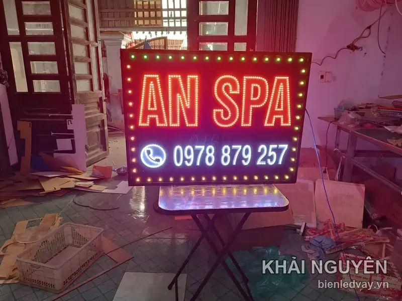 Biển vẫy AN SPA chữ đỏ viền vàng, số liên hệ trên biển đặt trên dải xanh dương, viền LED vàng xen xanh lá
