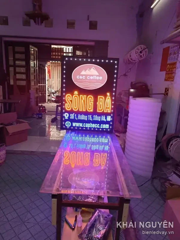 Biển vẫy LED C C Coffee thử sáng ban đêm, nền đen viền bóng tròn trắng, có chữ SÔNG ĐÀ đỏ cam và logo núi bầu dục.