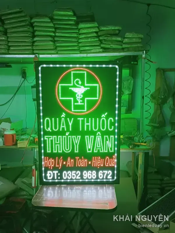 Biển vẫy QUẦY THUỐC THÚY VÂN treo thử trên khung sắt trong xưởng, có chữ trắng và chữ thập xanh trong vòng tròn đỏ