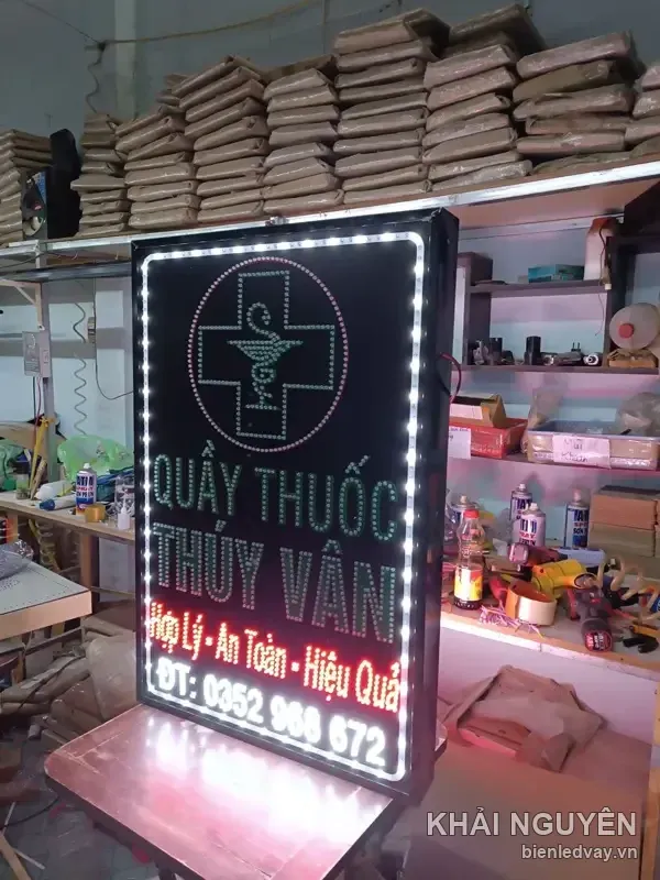 Ảnh biển vẫy Quầy Thuốc Thúy Vân chụp dưới ánh đèn hồng của xưởng, số điện thoại sáng ở dưới cùng