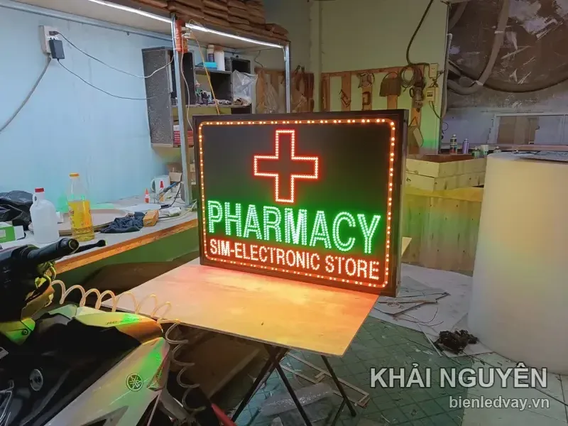 Biển vẫy nhà thuốc PHARMACY SIM-ELECTRONIC STORE, chữ thập LED đỏ, khung viền sẫm, viền LED bóng tròn vàng