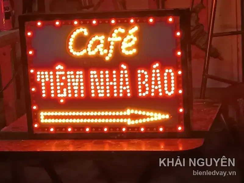 Biển vẫy LED Café TIỆM NHÀ BÁO, chữ vàng và đỏ ghép bằng bóng tròn, có mũi tên chỉ hướng, viền bóng đỏ trên khung đen.