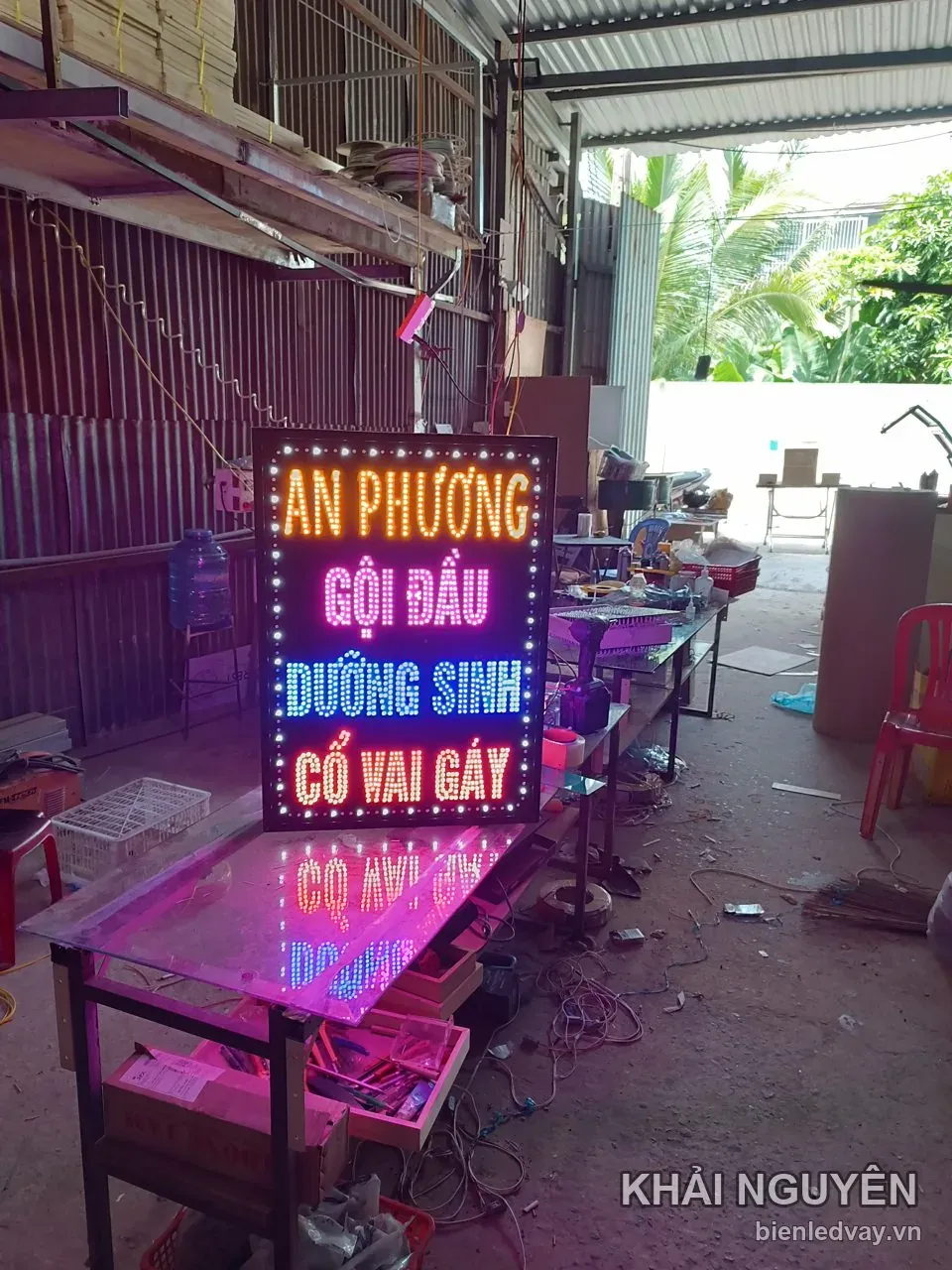 Biển vẫy An Phương sáng đèn nhìn từ xa trong xưởng mái tôn, bốn dòng chữ cam, hồng, xanh dương và cam