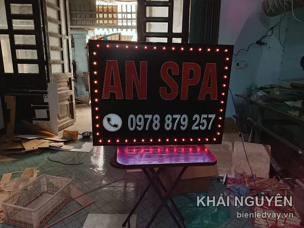 Biển vẫy AN SPA chữ đỏ trên nền đen, số liên hệ trên biển màu trắng, viền LED bóng tròn đỏ đang sáng