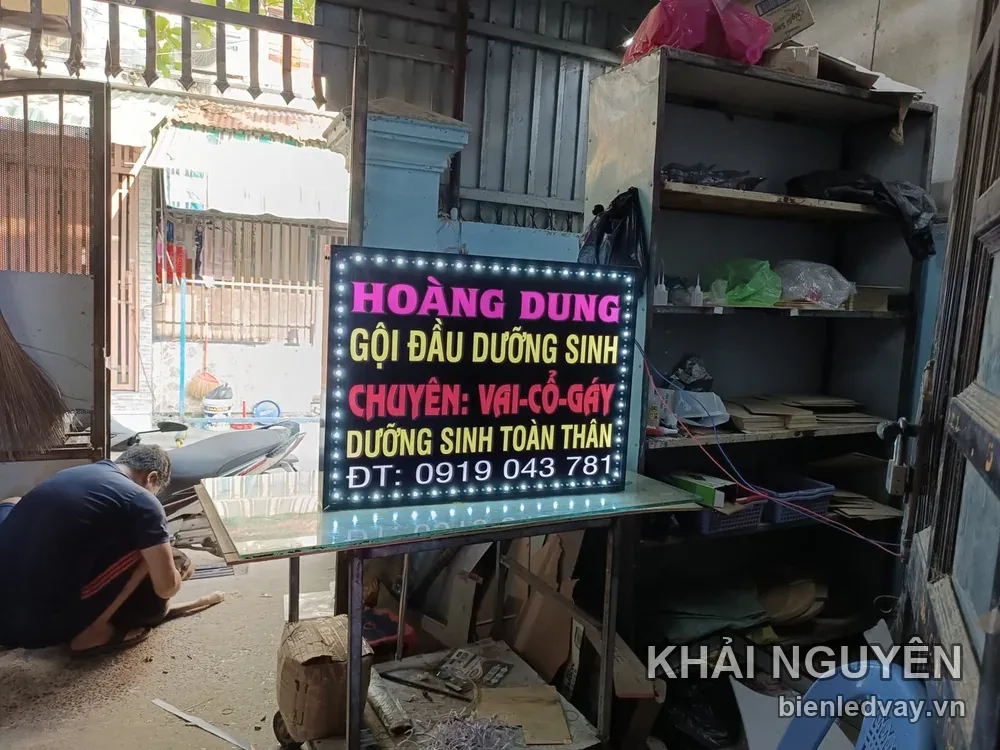Ảnh chính diện biển vẫy Hoàng Dung gội đầu dưỡng sinh, chữ LED hồng vàng đỏ, có số điện thoại và viền bóng trắng
