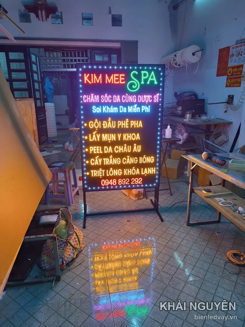 Biển vẫy Kim Mee Spa chân chữ A, chữ đỏ và xanh trên nền đen, liệt kê gội đầu, lấy mụn y khoa, peel da