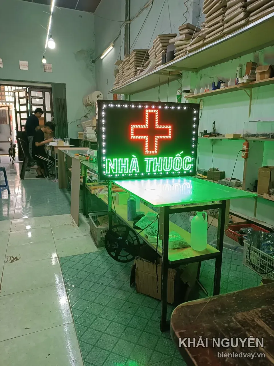 Biển vẫy Nhà Thuốc có chữ trắng xanh, chữ thập LED đỏ nổi bật trên nền đen và viền LED bóng tròn trắng.