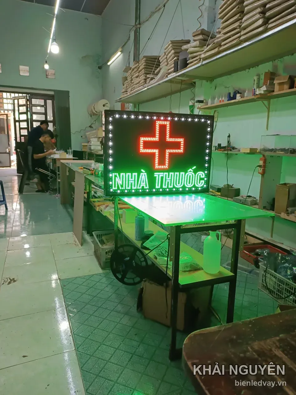 Biển vẫy NHÀ THUỐC đang thử sáng tại xưởng, có nền đen, chữ xanh lá, chữ thập đỏ và viền bóng LED tròn trắng.