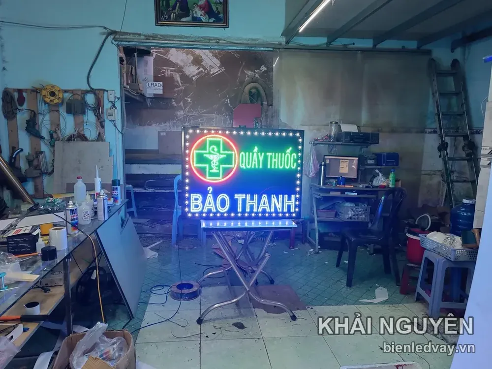 Biển vẫy QUẦY THUỐC BẢO THANH có chữ thập xanh lá trong vòng tròn đỏ, tên chữ trắng xanh và viền bóng vàng