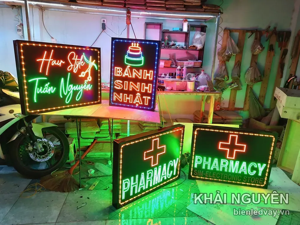 Bốn biển vẫy LED xếp cạnh nhau tại xưởng gồm hai biển Pharmacy thập giá đỏ, một biển tóc và một biển bánh sinh nhật
