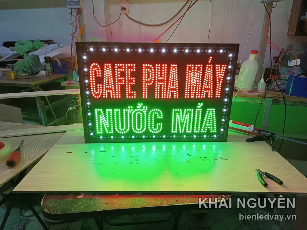 Biển nền đen viền bóng LED trắng, có chữ LED đỏ CAFE PHA MÁY và chữ LED xanh lá NƯỚC MÍA đang thử sáng tại xưởng.