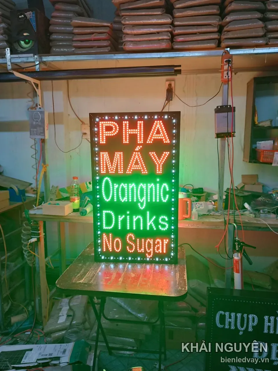 Biển vẫy đứng Pha Máy, chữ LED trắng Orangnic Drinks và chữ đỏ No Sugar trên nền đen