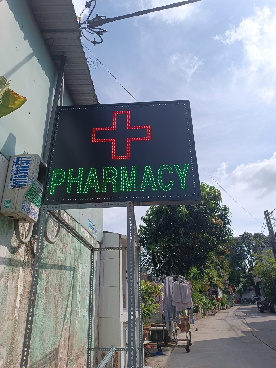 Bảng LED treo dọc hai mặt chữ Pharmacy và hình chữ thập xanh gắn ở góc tường