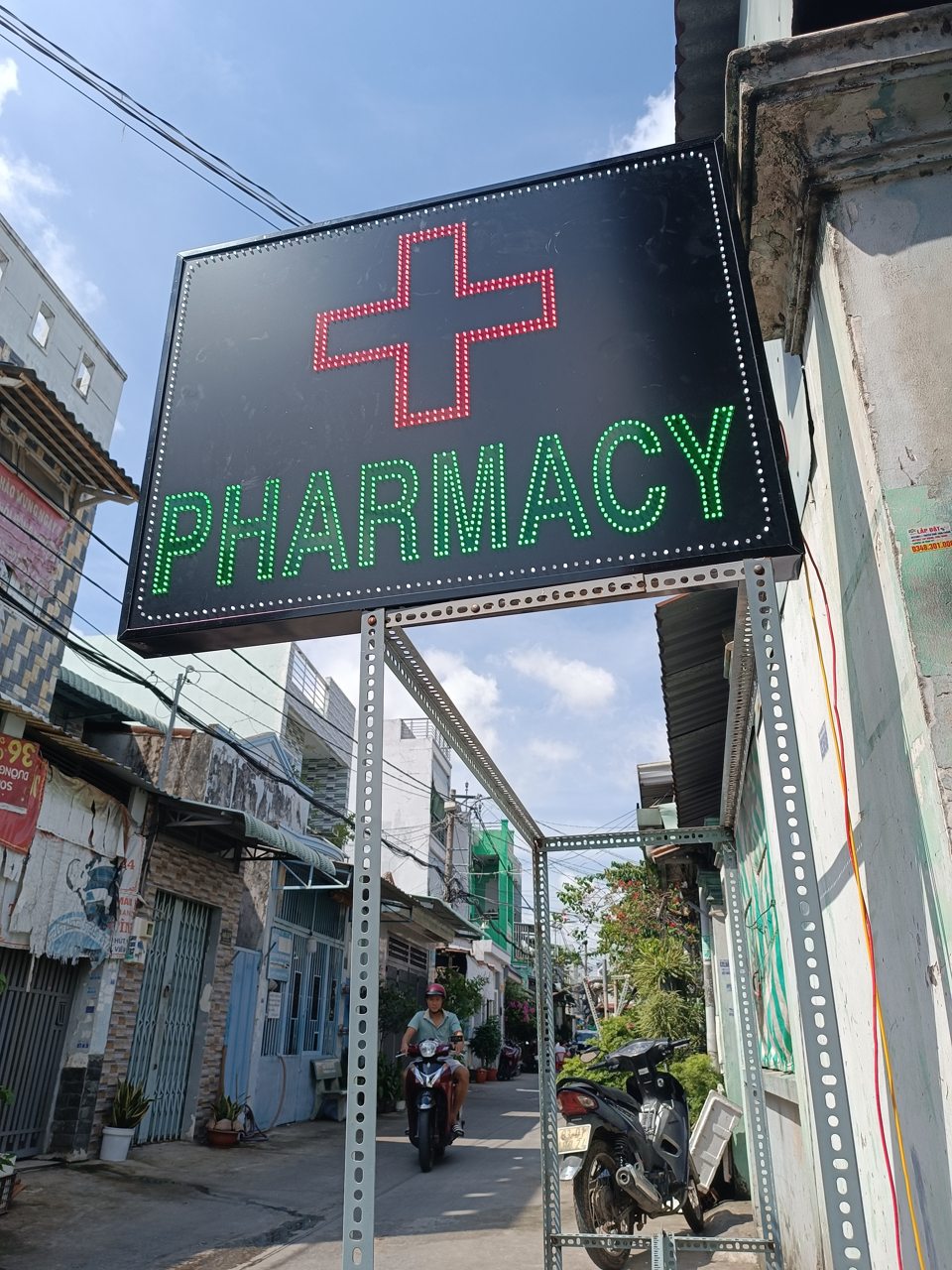 Biển vẫy nhà thuốc dạng hộp sáng có chữ Pharmacy và hình chữ thập xanh