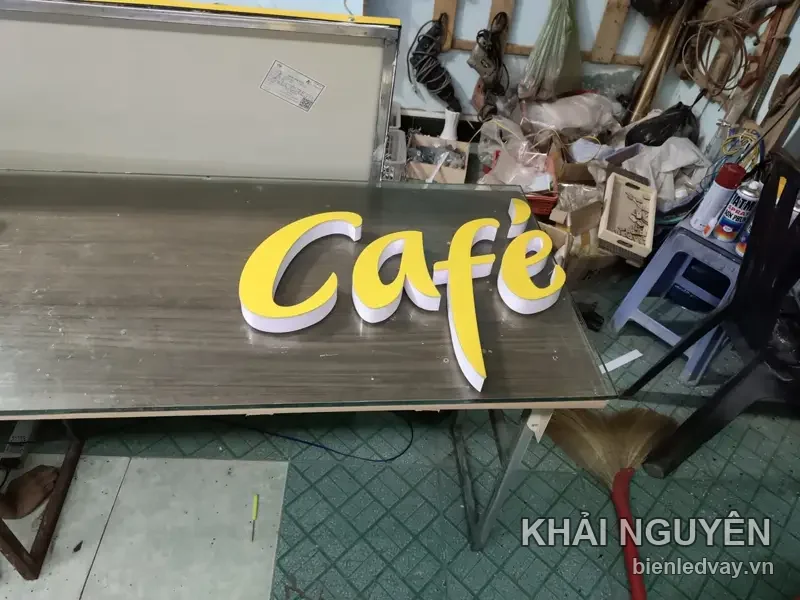 Chữ nổi mica Café mặt vàng thành trắng, kiểu chữ viết tay, đặt trên bàn xưởng chờ đóng gói lắp đặt