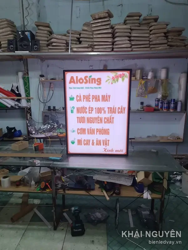 Hộp đèn AloSing mặt trắng viền cam khung đen, menu cà phê pha máy và cơm văn phòng, chụp toàn cảnh xưởng