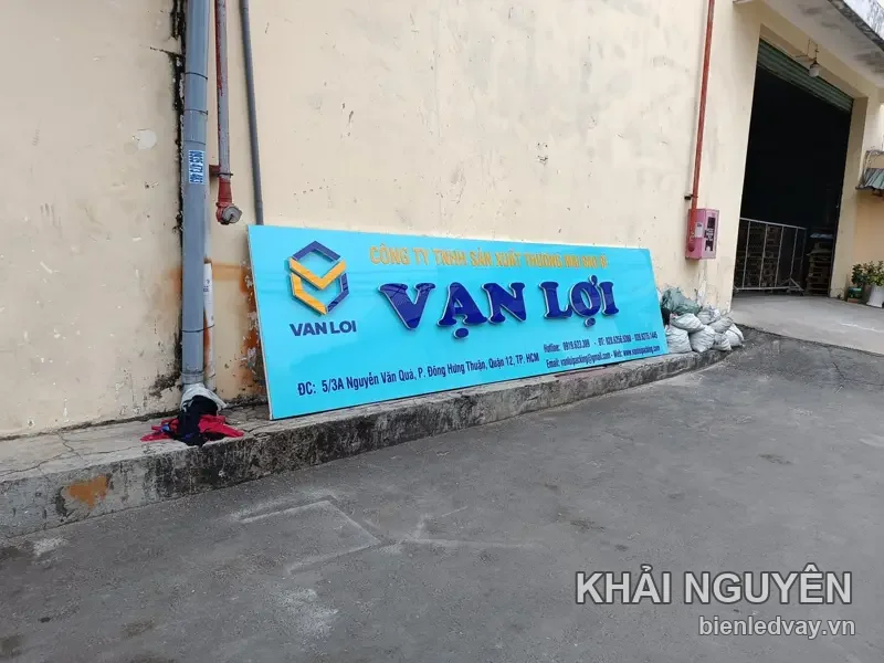 Bảng hiệu alu nền xanh dương, chữ nổi VẠN LỢI xanh đậm kèm logo hình khối, dựng dựa tường chờ lắp
