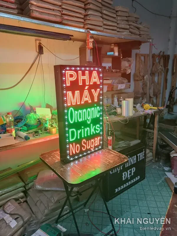 Biển vẫy LED đứng chữ Pha Máy đỏ trắng, Orangnic Drinks No Sugar xanh lá, sáng thử trên bàn trong xưởng