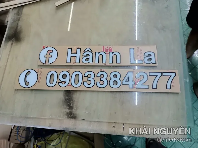 Chữ nổi mica trắng Hânn La kèm icon Facebook và dãy số liên hệ trên biển, còn dán màng bảo vệ trên bàn xưởng