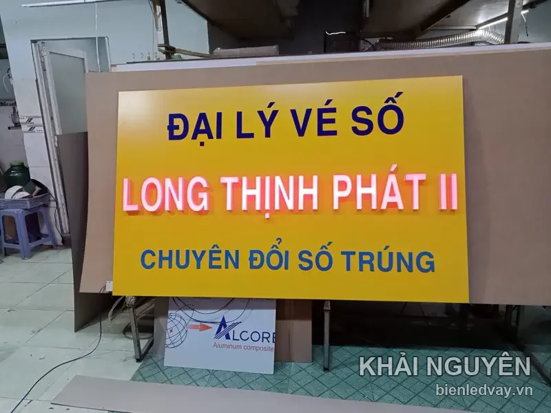 Bảng alu nền vàng gắn chữ nổi mica Đại lý vé số Long Thịnh Phát II, chữ hồng và xanh dương, dựng trong xưởng
