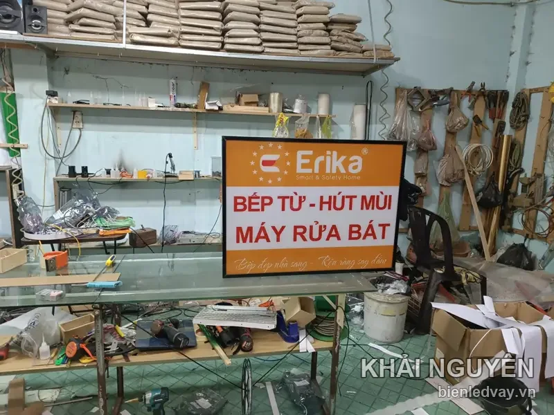 Biển hiệu Erika Smart - Safety Home nền cam, chữ đỏ BẾP TỪ - HÚT MÙI - MÁY RỬA BÁT, khung đen treo tại xưởng