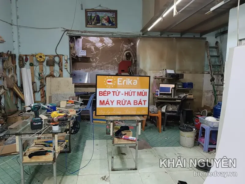 Hộp đèn Erika nền trắng, chữ BẾP TỪ - HÚT MÙI và MÁY RỬA BÁT màu cam, viền đen, dựng thử giữa xưởng