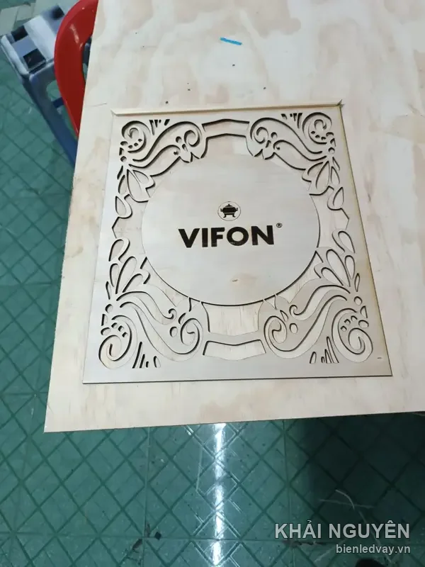 Tấm gỗ CNC khắc logo VIFON, hoa văn cắt lộng viền quanh, đặt trên bàn thi công xưởng Khải Nguyên
