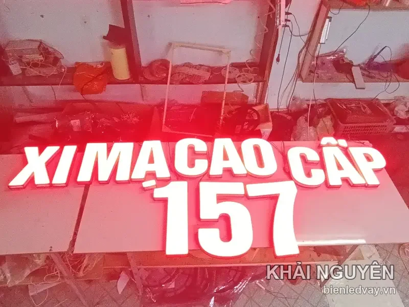 Chữ nổi mica trắng Xi Mạ Cao Cấp 157 hắt đèn LED đỏ, đặt trên bàn xưởng chờ nghiệm thu