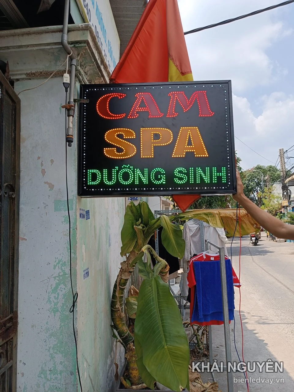 Biển vẫy LED chữ CAM SPA đỏ vàng, Dưỡng Sinh xanh lá, một người giữ biển sát tường trước cửa tiệm