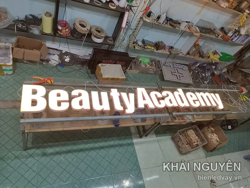 Chữ nổi mica Beauty Academy chữ trắng phát sáng, đặt trên giá thử đèn trong xưởng Khải Nguyên