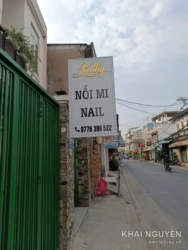 Hộp đèn nail Kathy nền trắng chữ Kathy màu vàng, dòng Nối Mi Nail đen và số liên hệ trên biển, gắn vươn ra vỉa hè