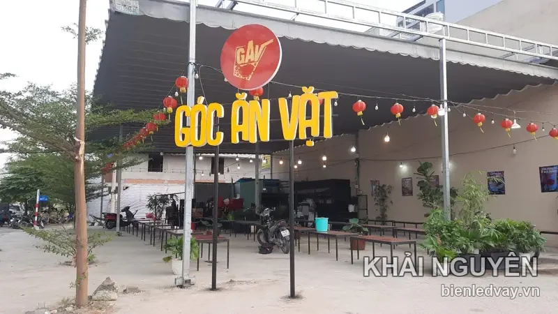 Chữ nổi GÓC ĂN VẶT màu vàng cùng logo GAV tròn đỏ trên mái quán, treo lồng đèn đỏ, quán ăn ngoài trời