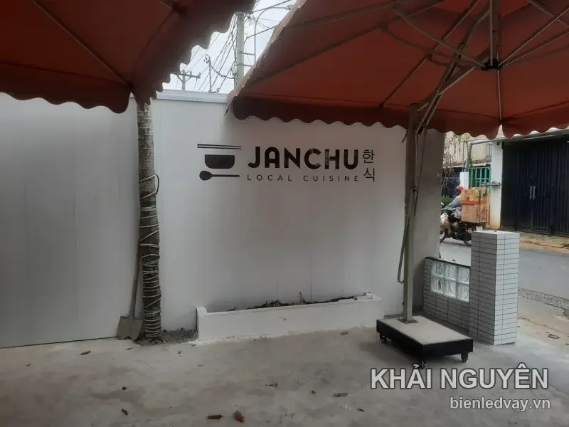 Chữ nổi JANCHU Local Cuisine màu đen gắn tường trắng quán Hàn, kèm logo tô đũa và chữ 한식
