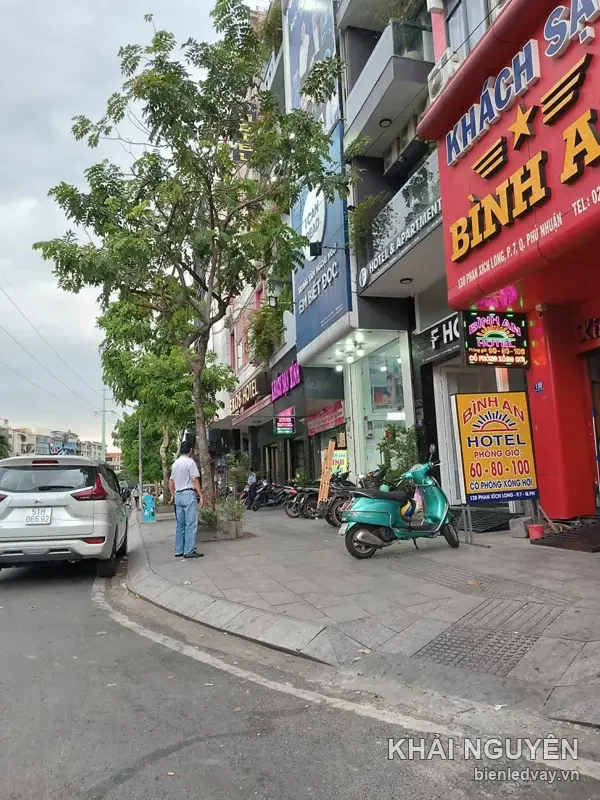 Mặt tiền đỏ Khách sạn Bình An, chữ nổi KHÁCH SẠN xanh dương và BÌNH AN vàng, kèm bảng đứng báo giá phòng giờ