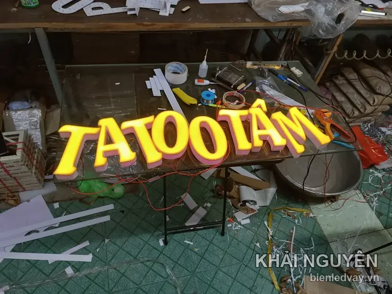 Chữ nổi mica TATOO TÂM mặt vàng hông hồng, gắn trên đế, đang lắp ráp tại xưởng Khải Nguyên