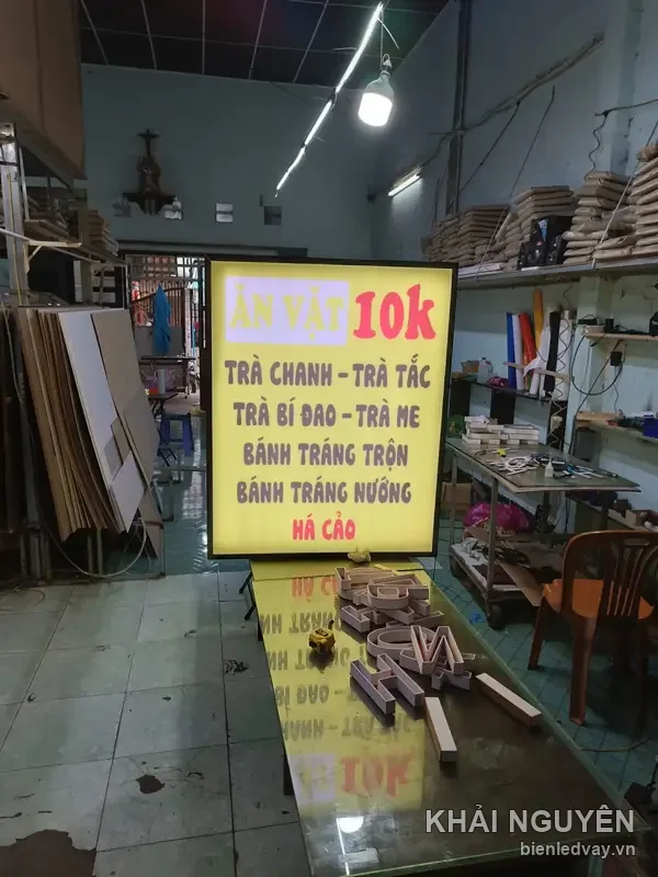 Hộp đèn nền vàng khung đen, chữ ĂN VẶT 10k hồng, menu trà chanh trà tắc trà bí đao bánh tráng trộn há cảo