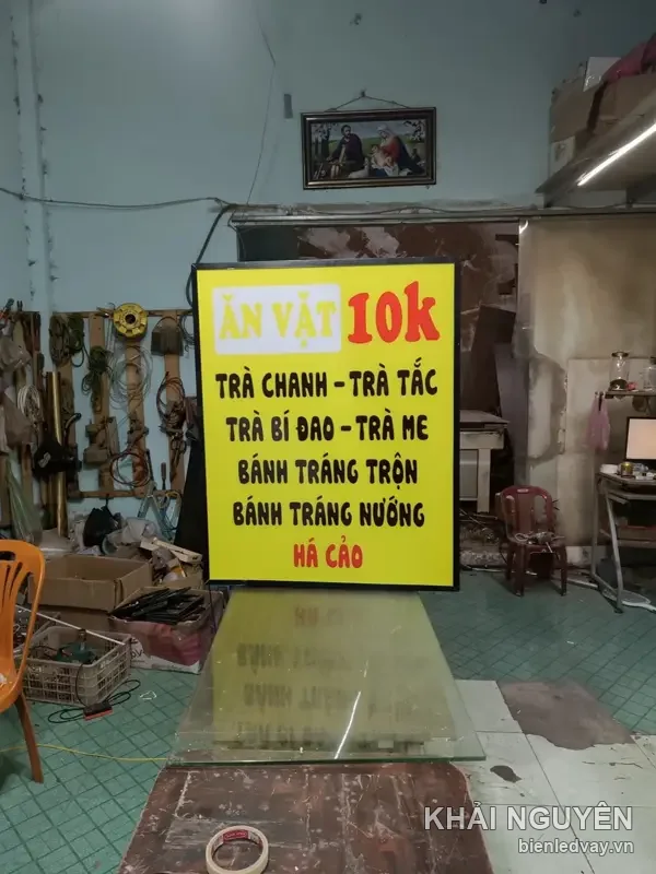 Hộp đèn quán trà chanh nền vàng chữ đen, dòng ăn vặt 10k và bánh tráng trộn, khung viền đen, mới hoàn thiện tại xưởng